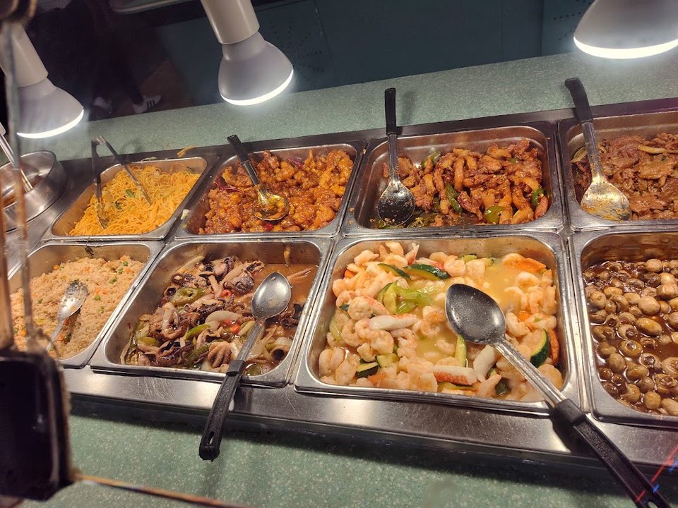 Seafood dishes and orange chicken on display.